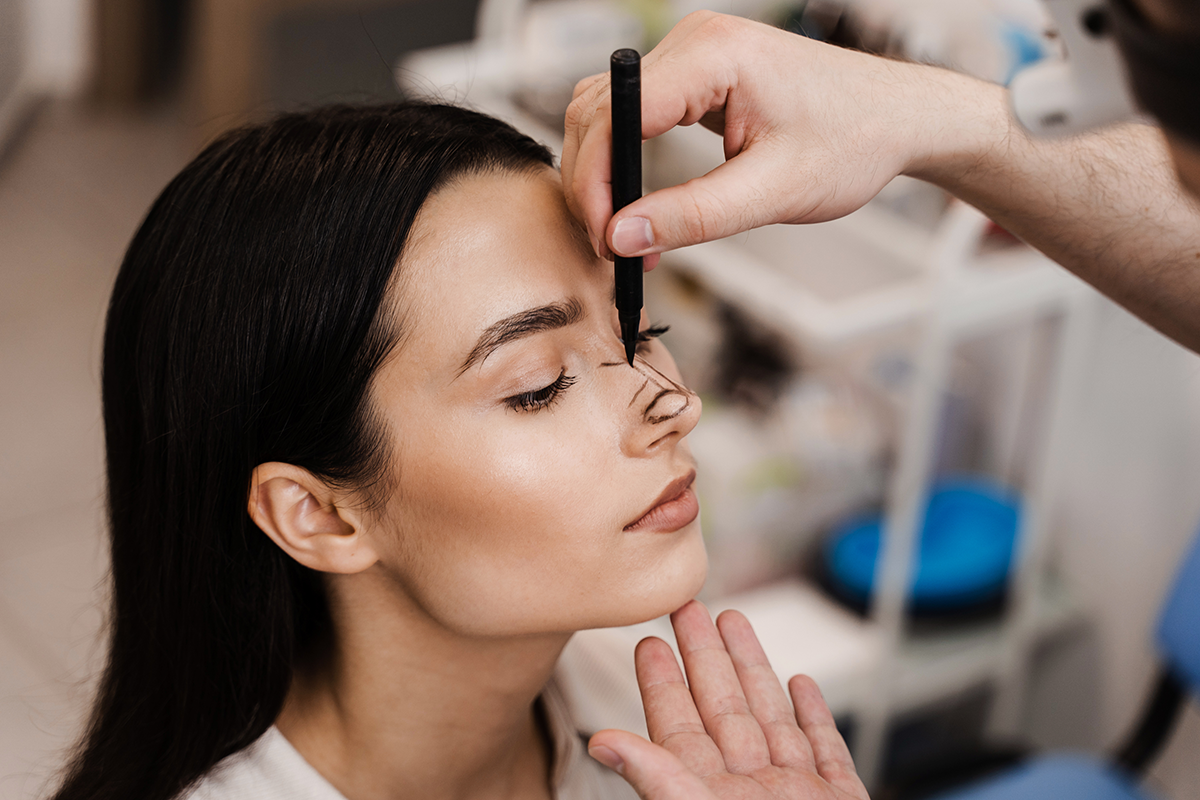 doctor is drawing mark up lines on nose before rhinoplasty surgery