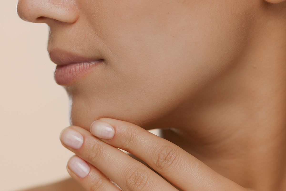 extreme close up shot of young woman with perfect skin strokes her jaw line and chin