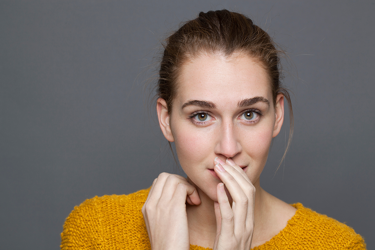 girl thinking with shy hand gesture for discretion and shyness