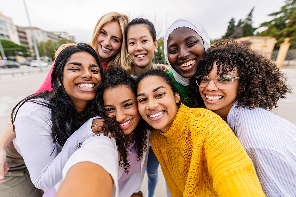 happy young group of diverse women taking selfie portrait at city street