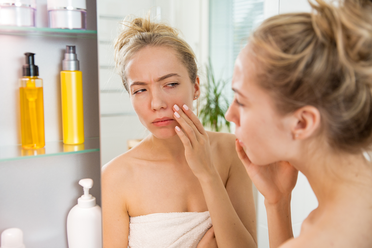 unhappy girl standing in towel looking in the mirror