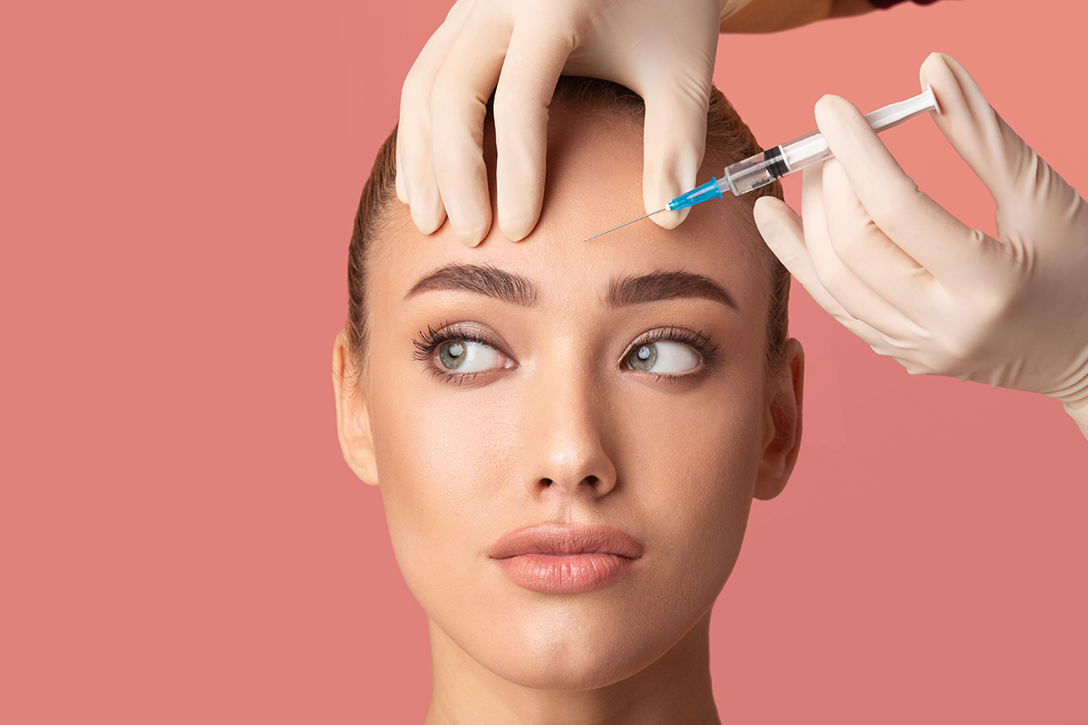 young woman receiving botox beauty injection in forehead