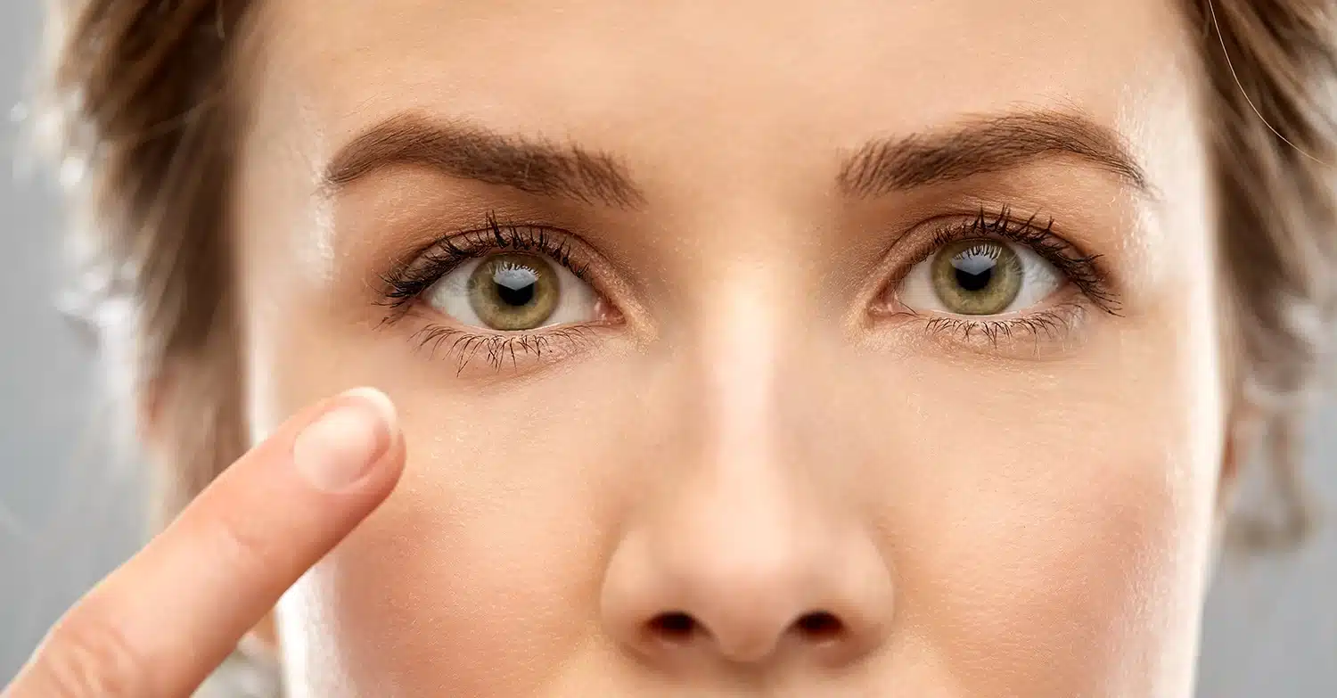Extreme close-up of a woman’s healthy hazel eyes as a finger points toward the lower eyelid area. Extreme close-up of a woman's healthy hazel eyes as a finger points toward the lower eyelid area.